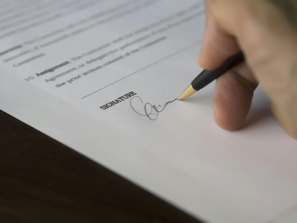 Deux personnes signant un contrat commercial dans un bureau professionnel